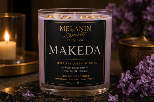 A 10 oz soy wax candle by Melanin Spirit Candle Co. named 'Makeda', in a clear glass jar with a black label and gold glitter accents.